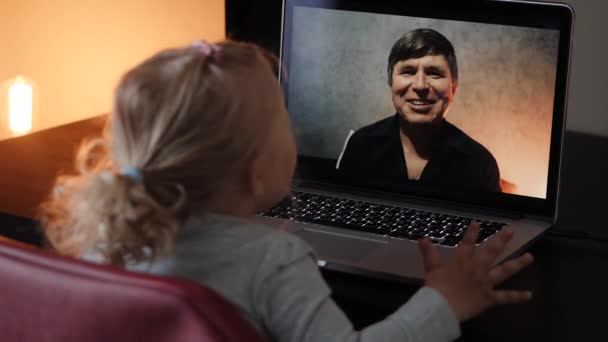 La niña en el video en el portátil envía un beso al abuelo en línea — Vídeos de Stock