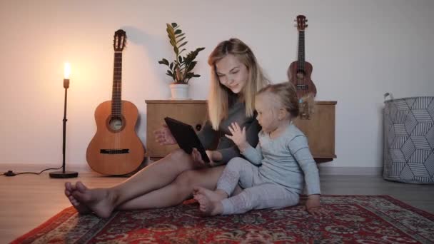 Мати показує маленьку доньку планшетні відео з мультфільмами — стокове відео