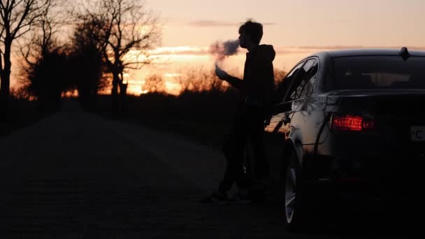 Silhouet van een jonge man op de weg Elektronische sigaretten roken — Stockvideo