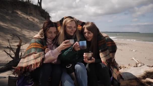 Tres mujeres jóvenes al aire libre bebiendo té caliente hablando y calentándose — Vídeo de stock