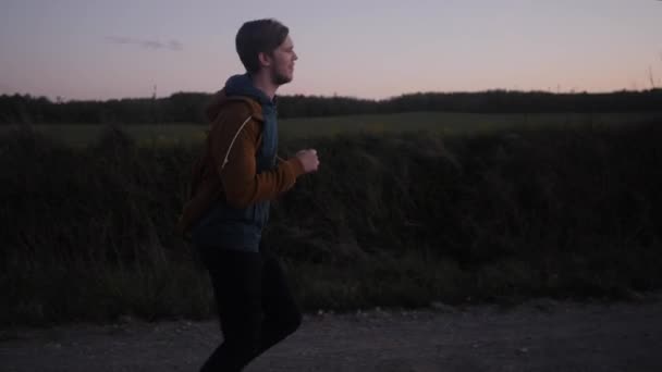 夕方道路の若い男に沿ってジョギング — ストック動画