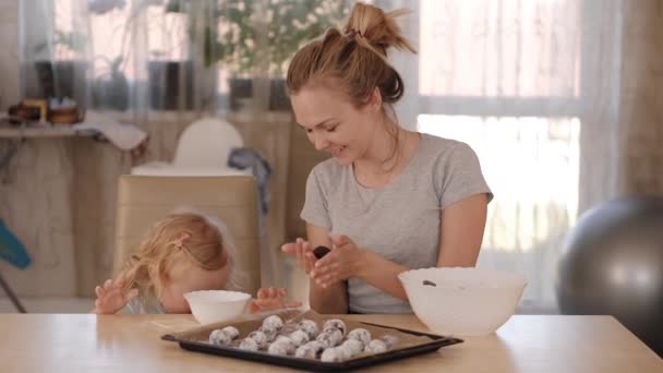 Mãe feliz e pequena filha preparando biscoitos na cozinha — Vídeo de Stock