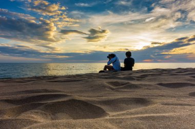 Siluet insanlar sahilde günbatımı için bekliyor.