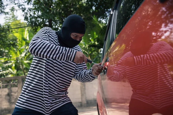 Car thief trying to unlock a car by screwdriver