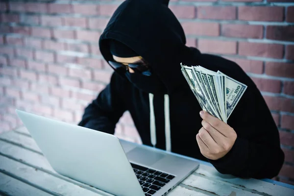 Počítačový hacker ukazující peníze s jeho počítače laptop — Stock fotografie