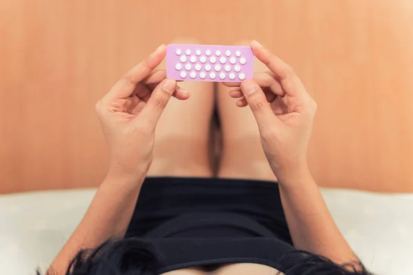 Mulher asiática segurando pílulas contraceptivas no quarto de cama, Saúde — Fotografia de Stock