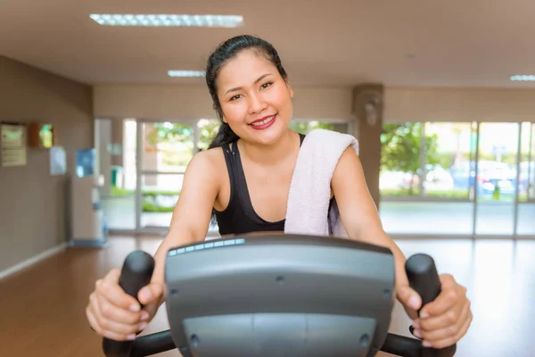 Asiática mujer entrenamiento en el ciclismo en gimnasio de fitness — Foto de Stock