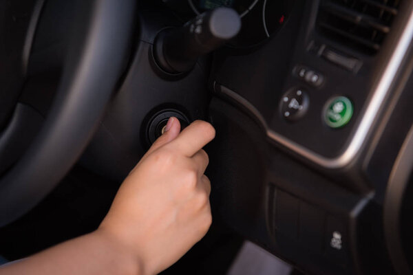 Close-up portrat of woman hand inserting key to turn on/off car