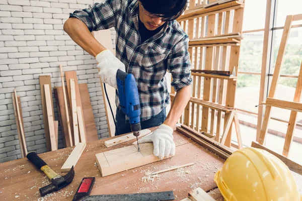 Carpenter Man is Working Timber Woodworking in Carpentry Shop, Craftsman is Screw Coring Timber Frame for Wooden Furniture in Workshop. Workmanship and Job Occupation Concept