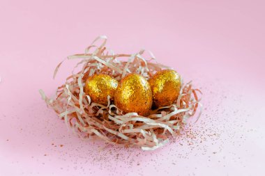 Paskalya altın madalyalı yumurtalar pembe arka planda yuvada. Metin için en az paskalya konsepti kopyalama alanı. 