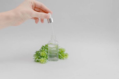 Kadın el ele tutuşan pipet. Hyaluronik asit damlası transparant cam şişe. Cilt bakımı ve sağlık