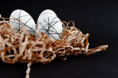 Paskalya altınları ve siyah arka planda yuvada beyaz yumurtalar. Metinler için minimum paskalya konsepti kopyalama alanı. Üst yatay görünüm