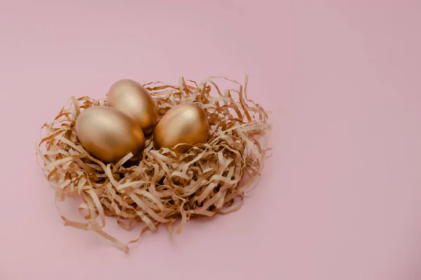 Ovos decorados de ouro de Páscoa em ninho em fundo rosa. Espaço mínimo da cópia do conceito da Páscoa para o texto. Vista horizontal superior, flatlay . — Fotografia de Stock