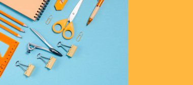 Okul konseptine geri dönelim. Renkli düz yatak. Kalemler, not defterleri, cetvel makasları ve ataçlar. Yatay görünüm kopyalama alanı