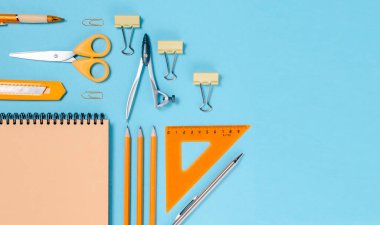 Okul konseptine geri dönelim. Renkli düz yatak. Kalemler, not defterleri, cetvel makasları ve ataçlar. Yatay görünüm kopyalama alanı