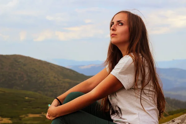 Kız bir dağ manzarasına bakıyor.