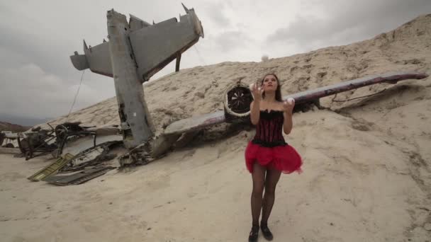 The girl juggles on a background of the destroyed aircraft — Stock Video