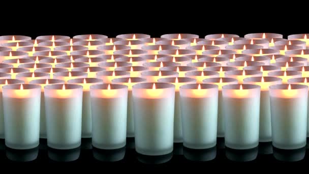 Muchas velas blancas sobre un fondo negro — Vídeo de stock
