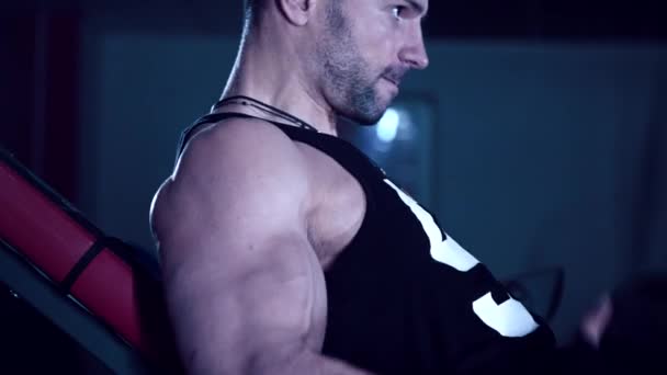 Brutal hombre sacude sus bíceps en el gimnasio — Vídeo de stock