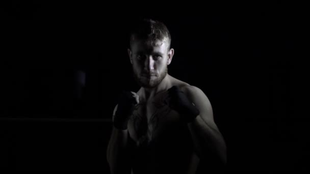 Bir boksör adam karanlıkta savaşan bir duruş duruyor — Stok video