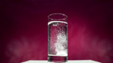 Aspirin tablet kırmızı bir arka plan üzerinde suda çözülür