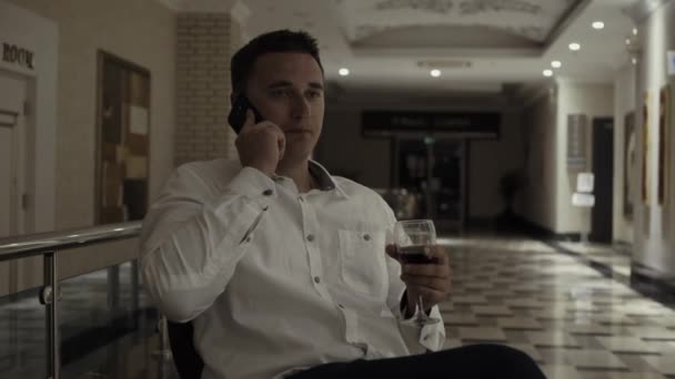 Sevimli bir adam bir kadeh kırmızı şarap bir restoranda içer. — Stok video