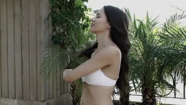 Piękna dziewczyna w białym kostiumie kąpielowym pozowanie na kamery w zwolnionym tempie — Wideo stockowe