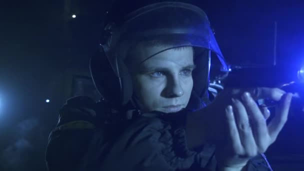Офицер полиции с пистолетом на фоне мерцающих мигалок — стоковое видео