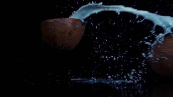 Кокос разбит в замедленной съемке на черном фоне — стоковое видео