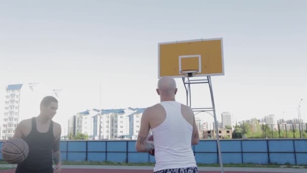 Två killar spelar basket på distriktets idrottsplats. — Stockvideo
