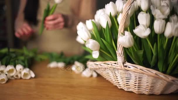 Witte tulpen in een mand. Op de achtergrond is een werkende bloemist zichtbaar-2. — Stockvideo