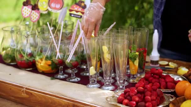 Gafas con ingredientes para limonada, de pie sobre la mesa. Cantinero pone los ingredientes en las copas . — Vídeo de stock