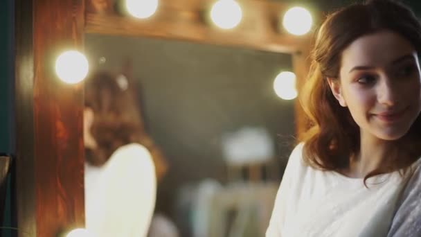 Beautiful bride posing in front of a mirror. Smiling in the rays of beautiful light. — Stock Video