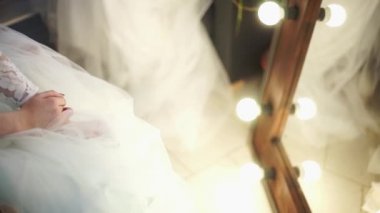 Çerçevede, güzel bir gelinlik, gelin el ve bir tasarımcı ile aydınlatma ayna.