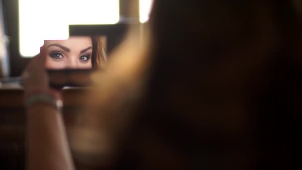 Meisje kijkt in een kleine spiegel, een mooie glimlach blik. — Stockvideo