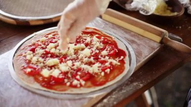 Şef pizza yapar, peynir domates sosu dökülen.