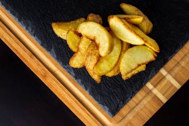 Patates yemek. Siyah ahşap masa üzerinde tuz ile fırında patates.