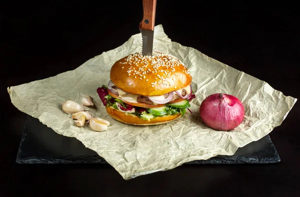 Hamburguesa con ajo está en papel kraft. Fondo de la pizarra negra . — Foto de Stock