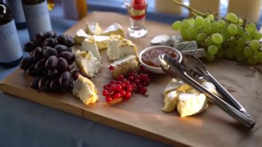 Brie, camambert, gauda, üzüm ve ahşap arka plan üzerinde kuş üzümü.