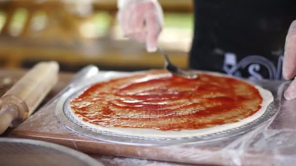 Fechar o molho de tomate é manchado sobre a massa de pizza . — Vídeo de Stock