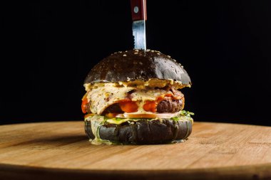 Marul, peynir, soğan ve domates ile lezzetli taze ev yapımı sığır eti burger close-up. Peynir bir köşesinde asılı. Siyah topuz.