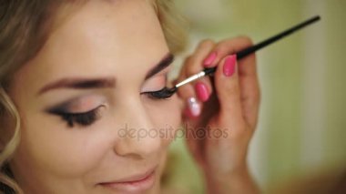 Ağırlıksız kirpik bir fırça ile boyanmıştır. Kadın ile sağlıklı genç yüz cilt için profesyonel makyaj.