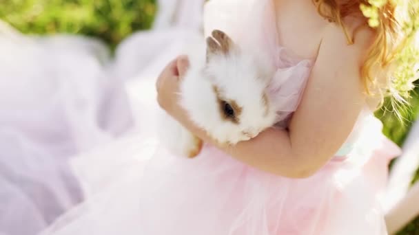 小さな赤い髪の少女がウサギを保持しています。. — ストック動画