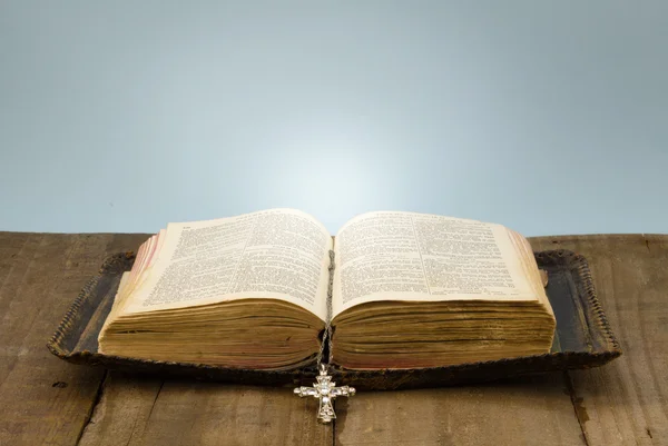 Couro velho coberto Bíblia Sagrada em mesa de madeira áspera com cruz de cristal Fotografias De Stock Royalty-Free