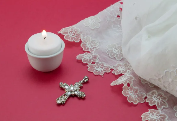 White vintage lace christening dress, candle and cross pendant isolated on red background — Stock Photo, Image