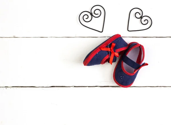 Overhead photo of pair of navy and red baby booties, heart metal — Stock fotografie