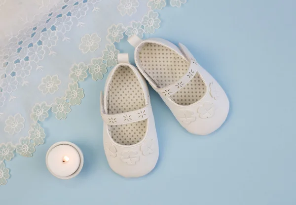 Pair of white baby booties on blue background with lace christen — ストック写真