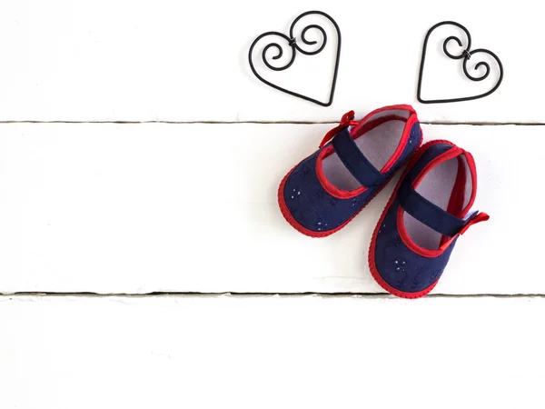 Overhead photo of pair of navy and red baby booties, heart metal shapes — ストック写真