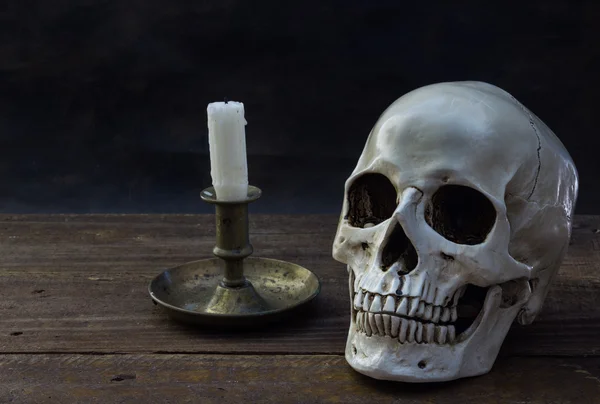 Череп человека со свечой на деревянном полу — стоковое фото
