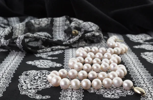 Close up of pearl necklace on black and white paisley chiffon pa — Stock Photo, Image